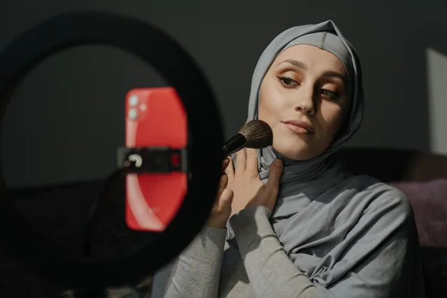 A Muslim woman in a hijab applies makeup for a tutorial indoors. Nine steps to reliable beauty creator partnerships operations