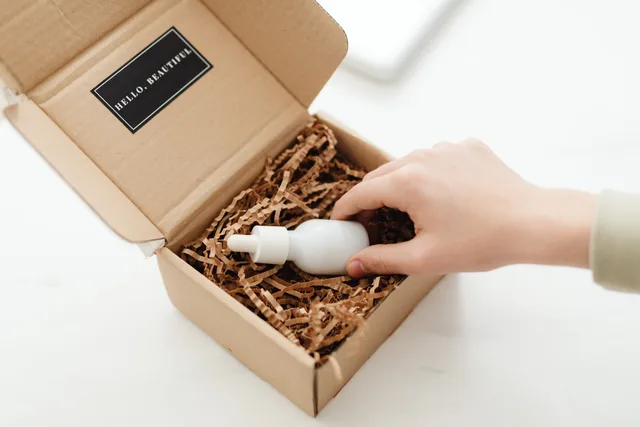 A hand unboxes a beauty product in a sustainable cardboard package with shredded paper. How to score beauty influencers' partnership options