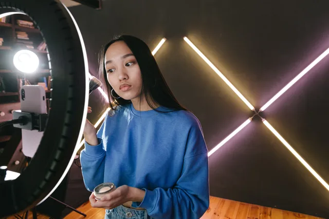 Woman applying makeup under ring light in modern indoor setting, perfect for beauty content creators. How do you measure beauty creator partnerships return on investment?