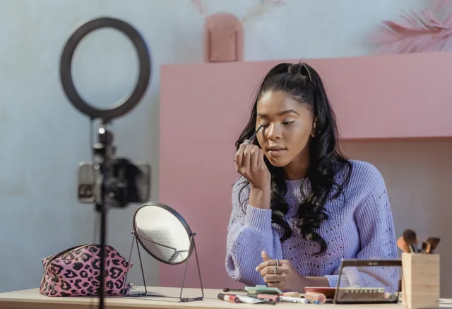Concentrated African American woman making makeup while filming beauty blog on smartphone in stylish room. Beauty creator partnerships strategy framework: four written parts before you brief anyone