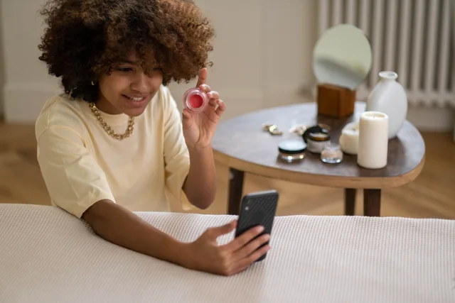 Young woman recording a video review of beauty products using a smartphone indoors. Beauty influencers: vendor due diligence checklist